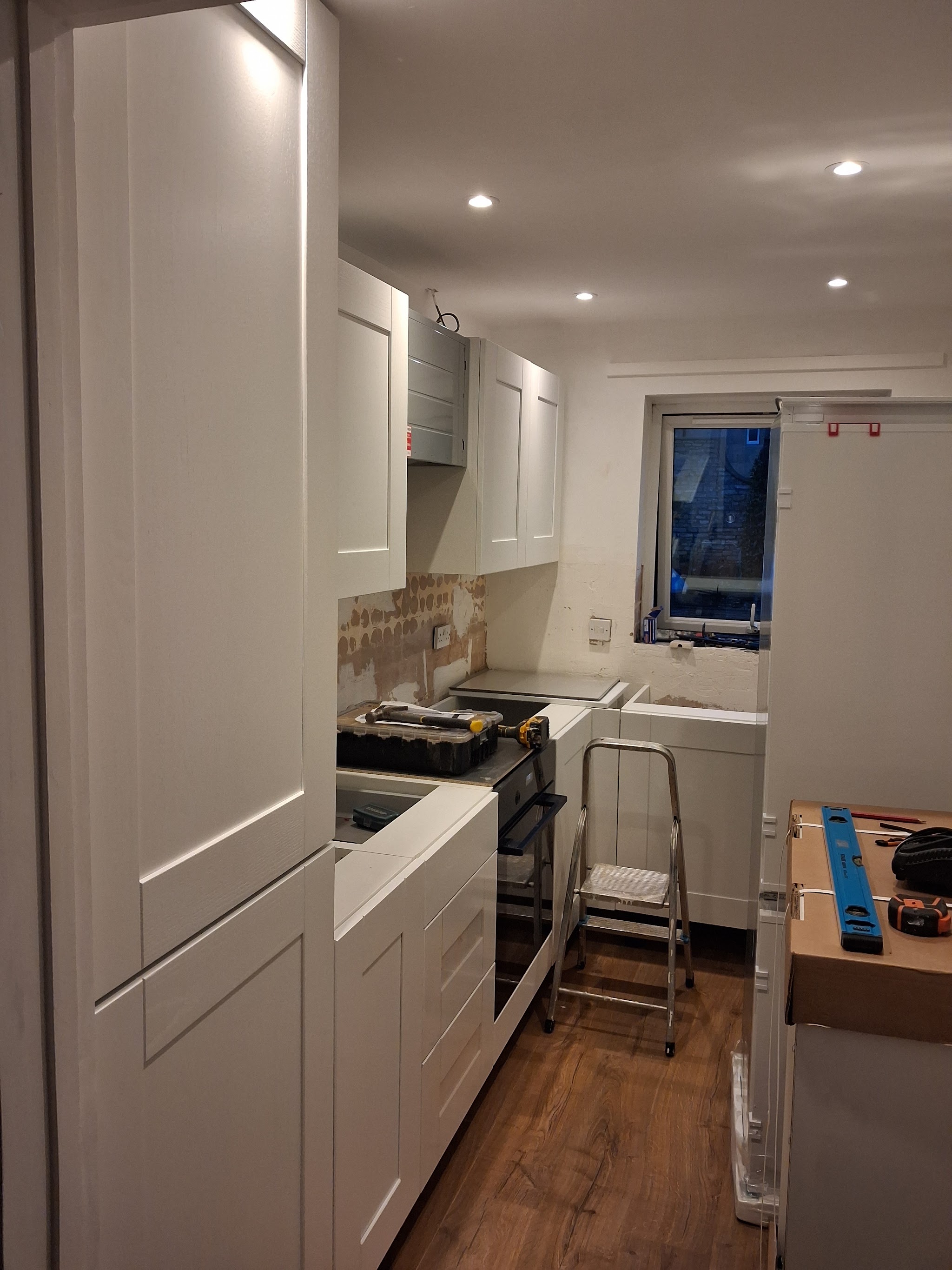 Galley kitchen part-way through fitting, with white shaker units