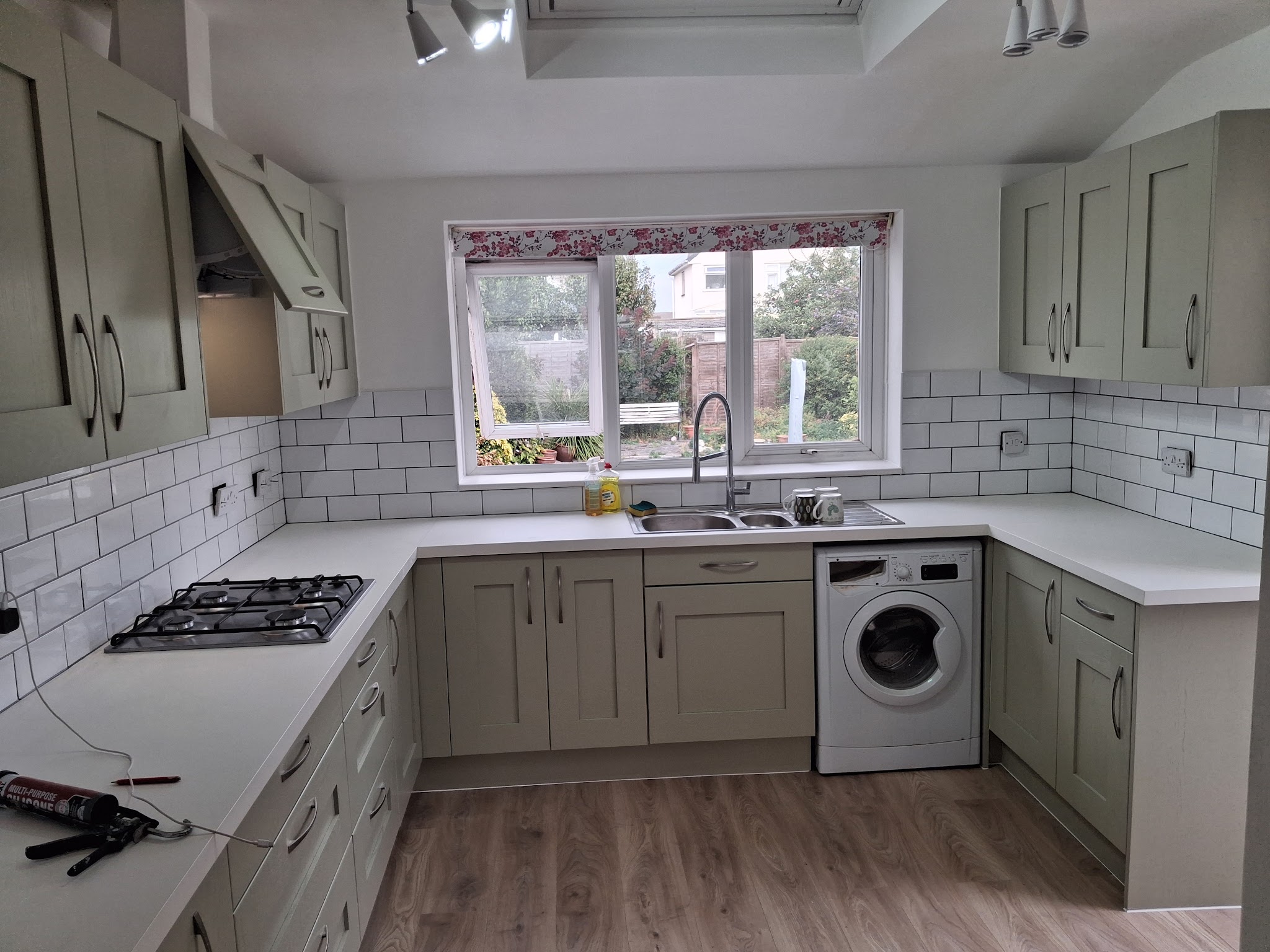Finished sage-green shaker kitchen with white metro tiles