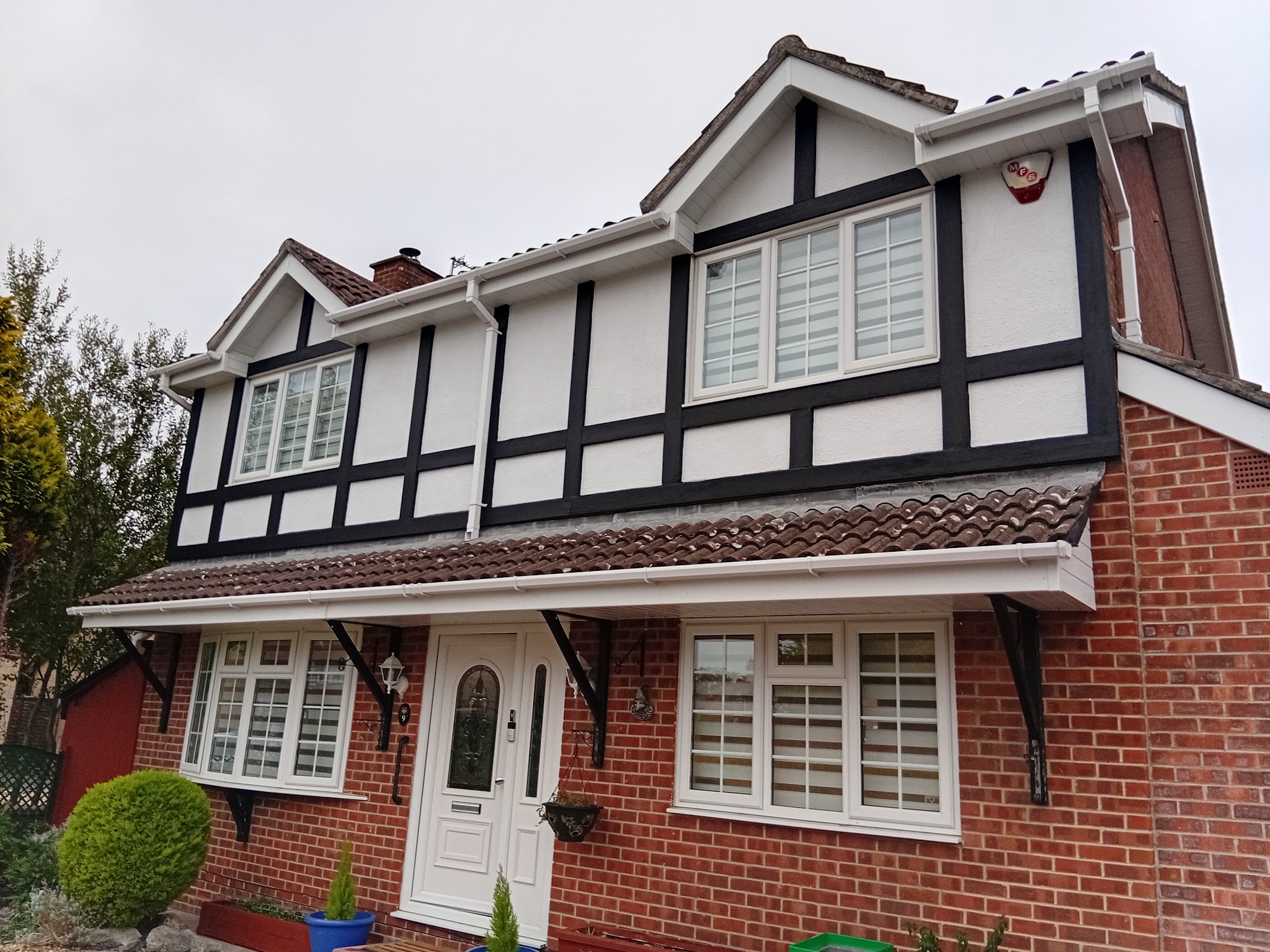 Mock-Tudor house front with white shutters and a porch canopy