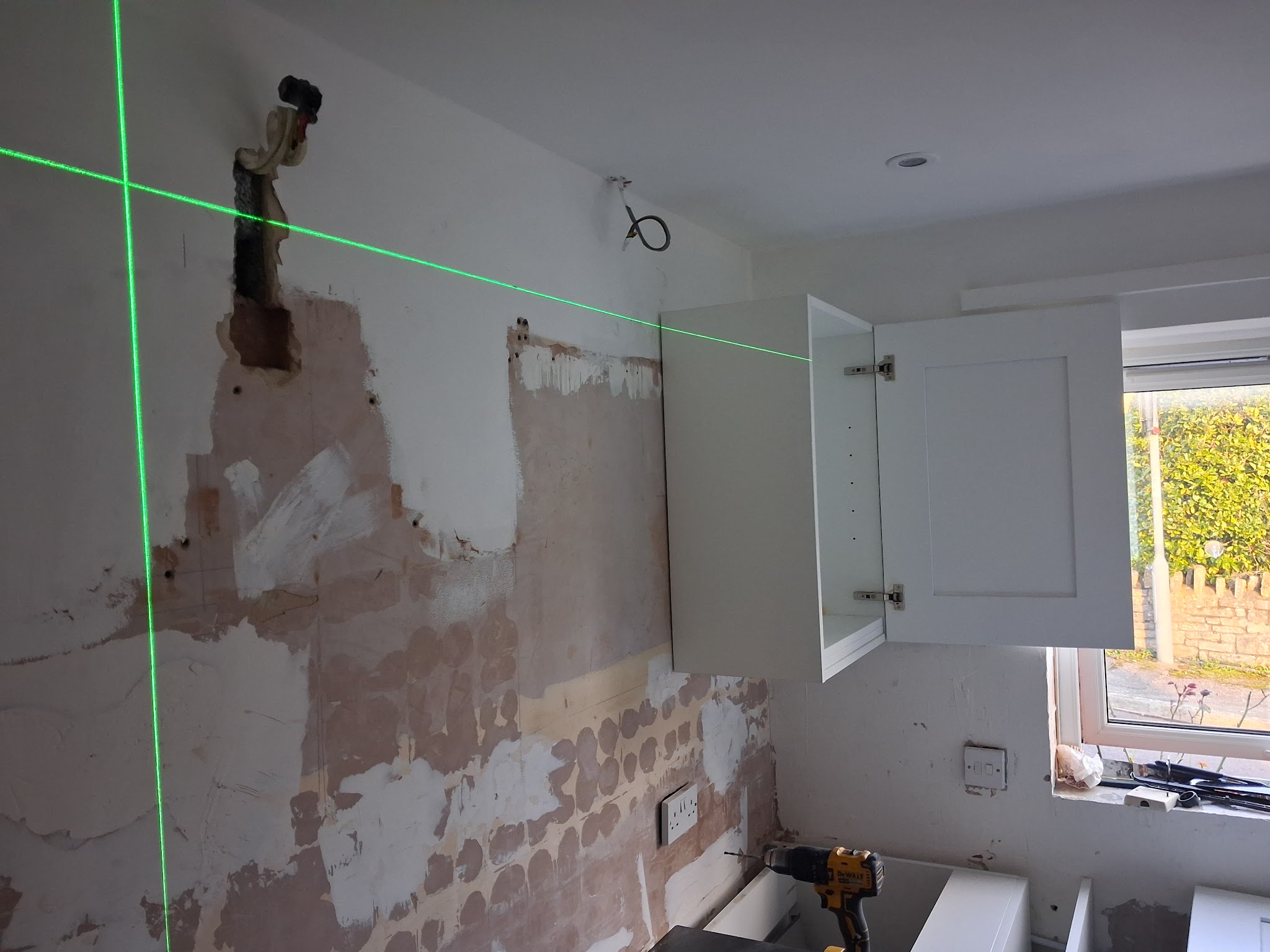 Kitchen wall being set out with a laser level before a wall unit goes up